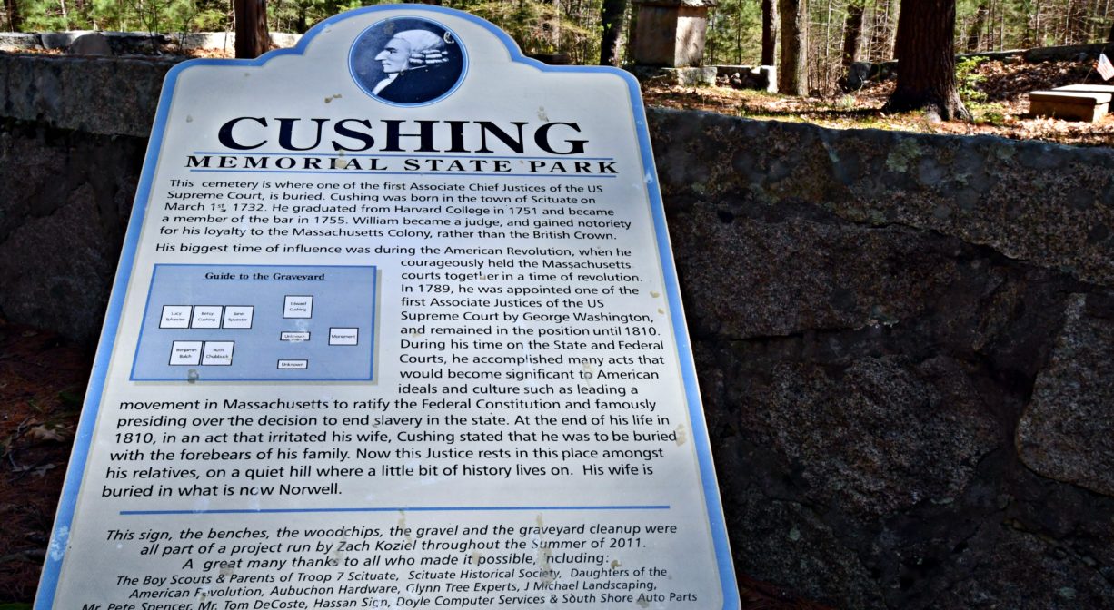 A close-up photograph of an interpretive sign with a stone wall in the background.