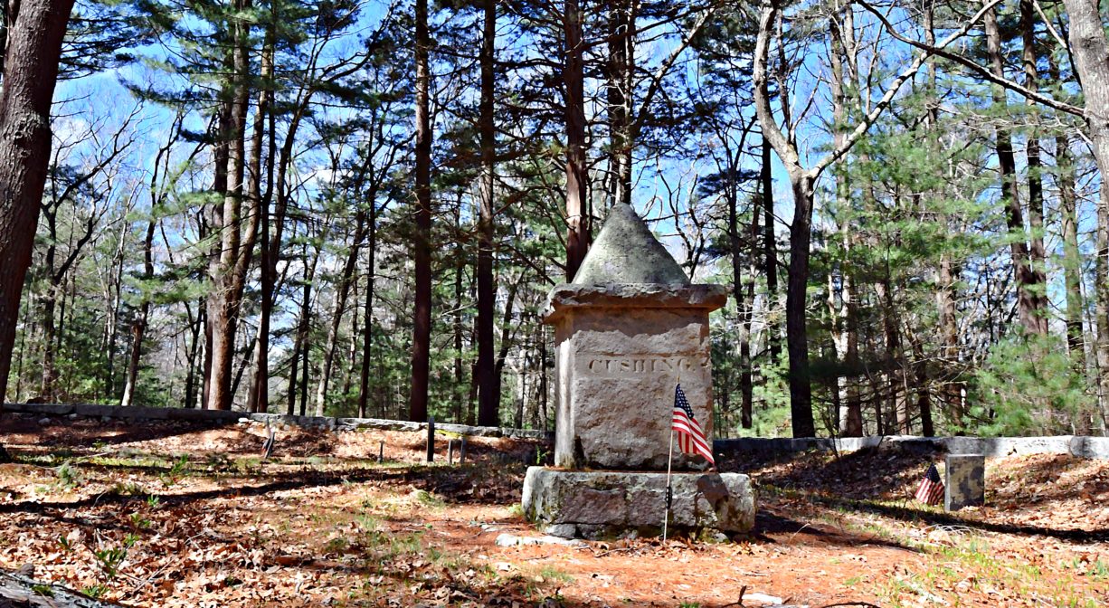 A photograph of a memorial in a wooded setting.