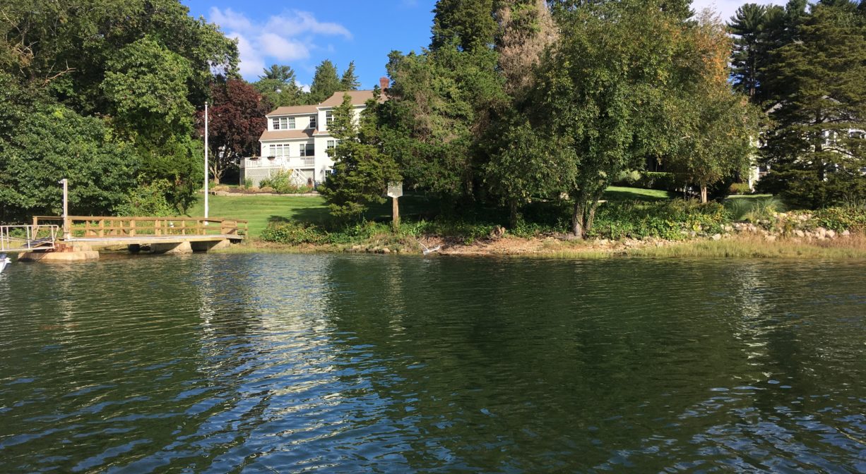 A distant photograph of a historic site with a bronze marker, viewed from the water.