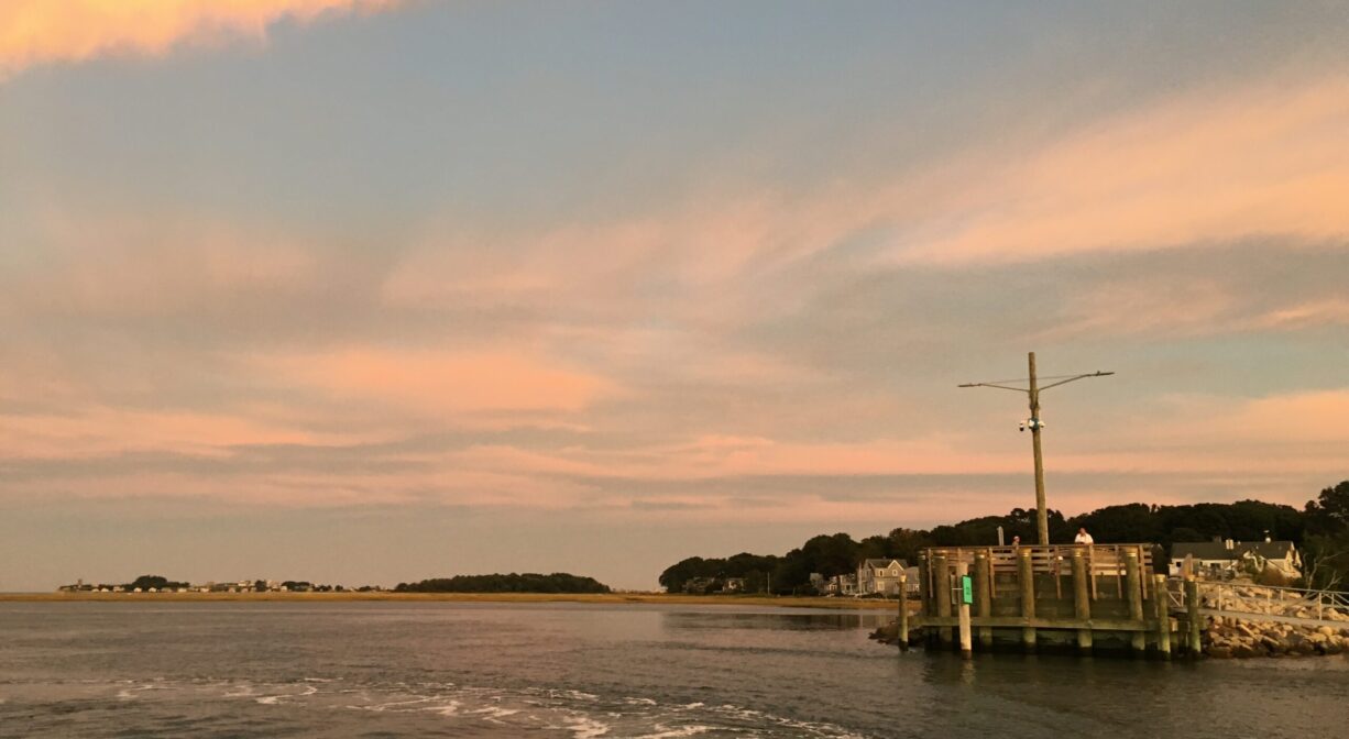 A small pier at the edge of a river, at sunset.