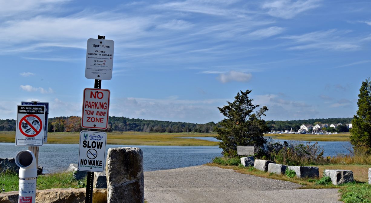 A photograph of a boat launch ramp with a river in the background, on a sunny day.