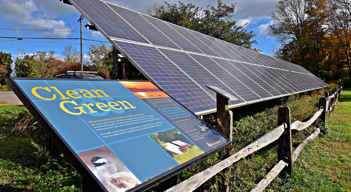 A photograph of a solar panel on a green field, with interpretive signage.