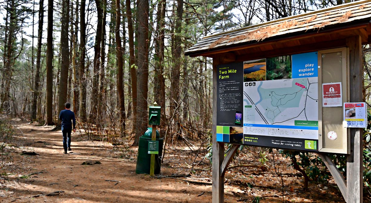 A photograph of an informational kiosk in a woodland setting.