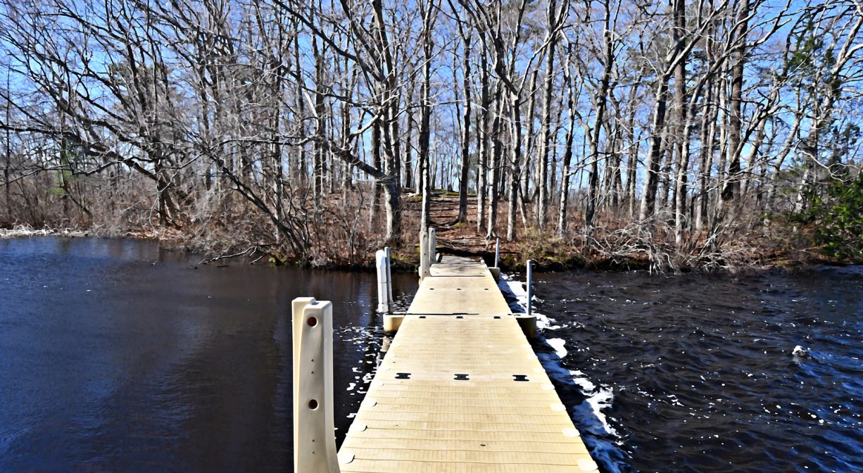 A photograph of a fishing pier extending into a pond.