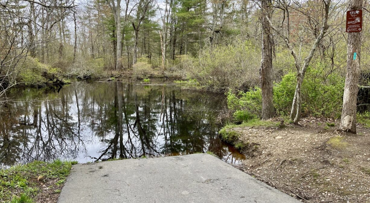 A photograph of a concrete boat ramp leading to a river.