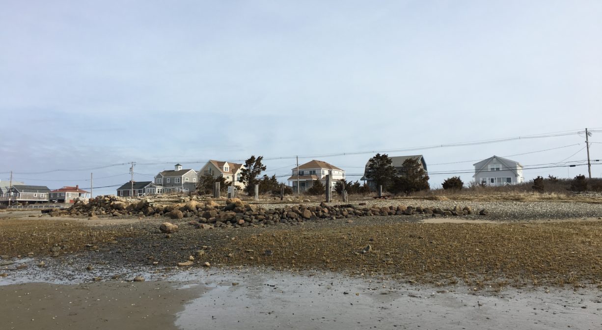 A distant photograph of a stone foundation with a low tidal area in the foreground.