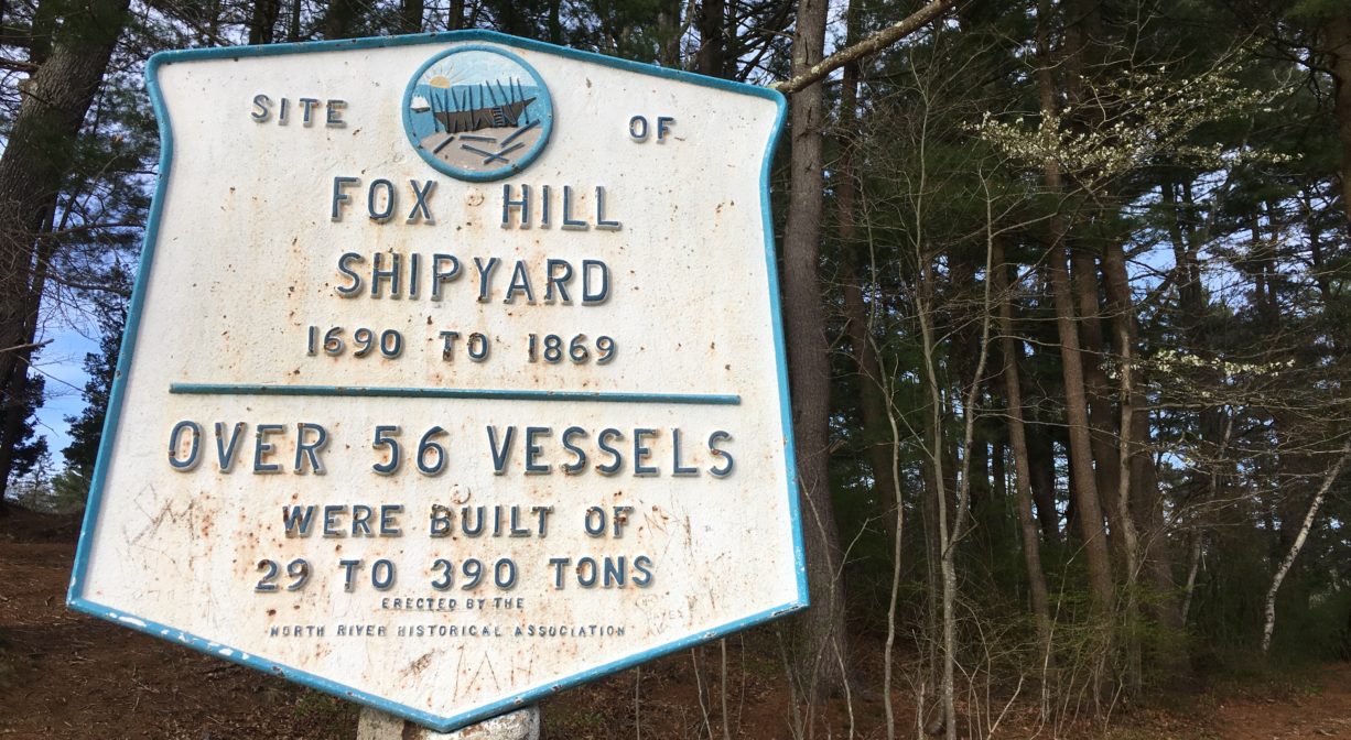 A photograph of a historic marker with a forest in the background.