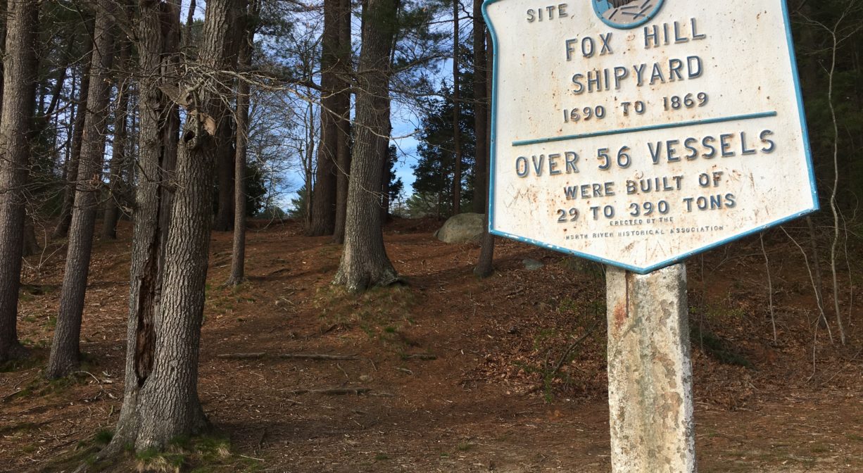 A photograph of a historic marker with a forest in the background.