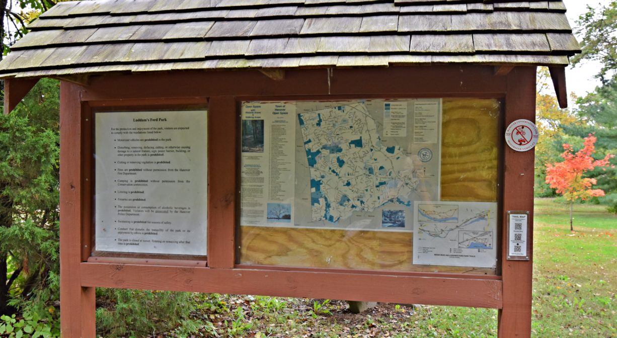 A photograph of an informational kiosk within a green park.