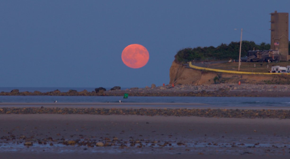 A photograph of Fourth Cliff and its guard tower with a bright pink full moon.