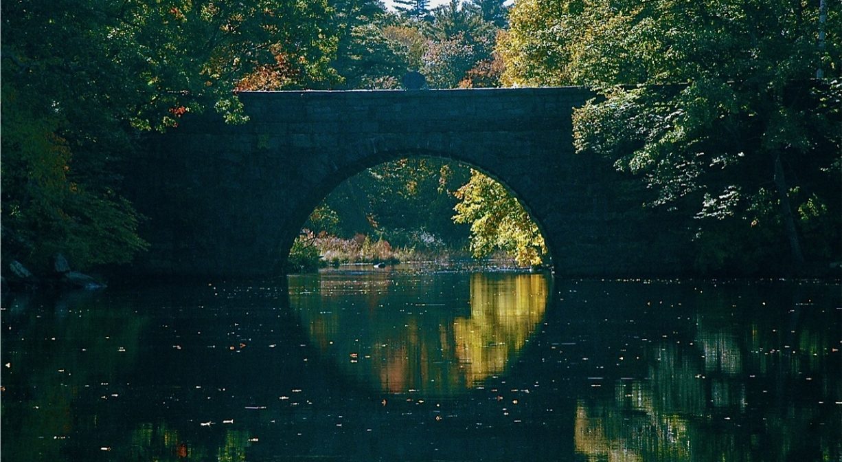 A photograph of a stone bridge spanning a river.