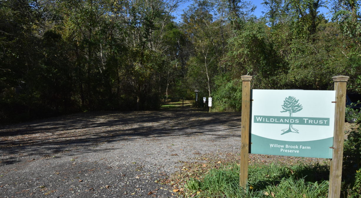 A photograph of a property sign beside a parking area.