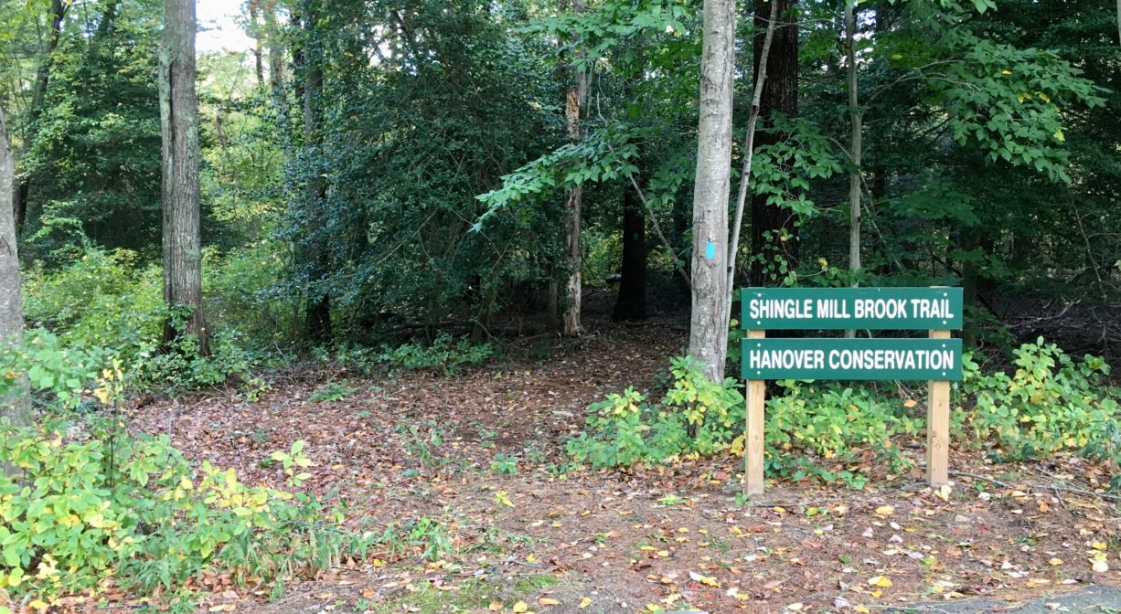 A photograph of a trailhead and a property sign.