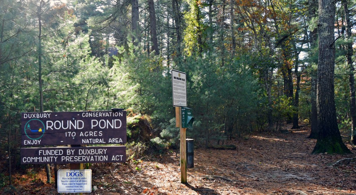 A photograph of a property sign and a forest trailhead.