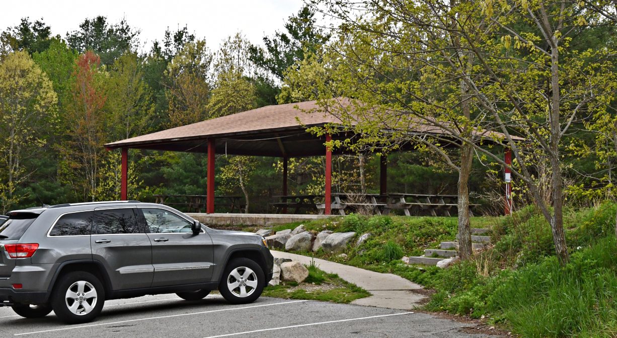 A photograph of a parking area with a pavilion in the background.