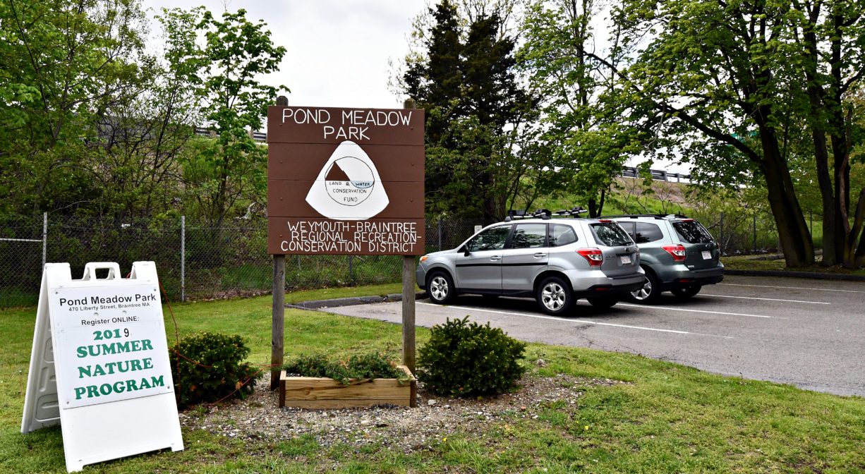 A photograph of paved parking area and a property sign.