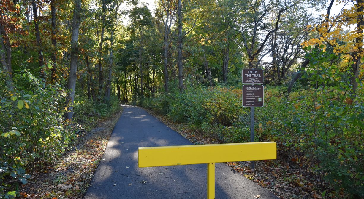 Photograph of trail entrance in wooded setting.
