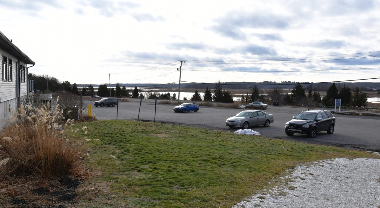 A photograph of a large parking area with grass in the foreground.
