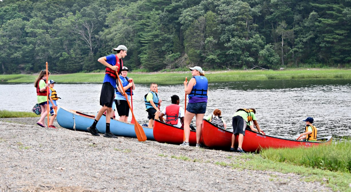 A photograph of several children getting into canoes.