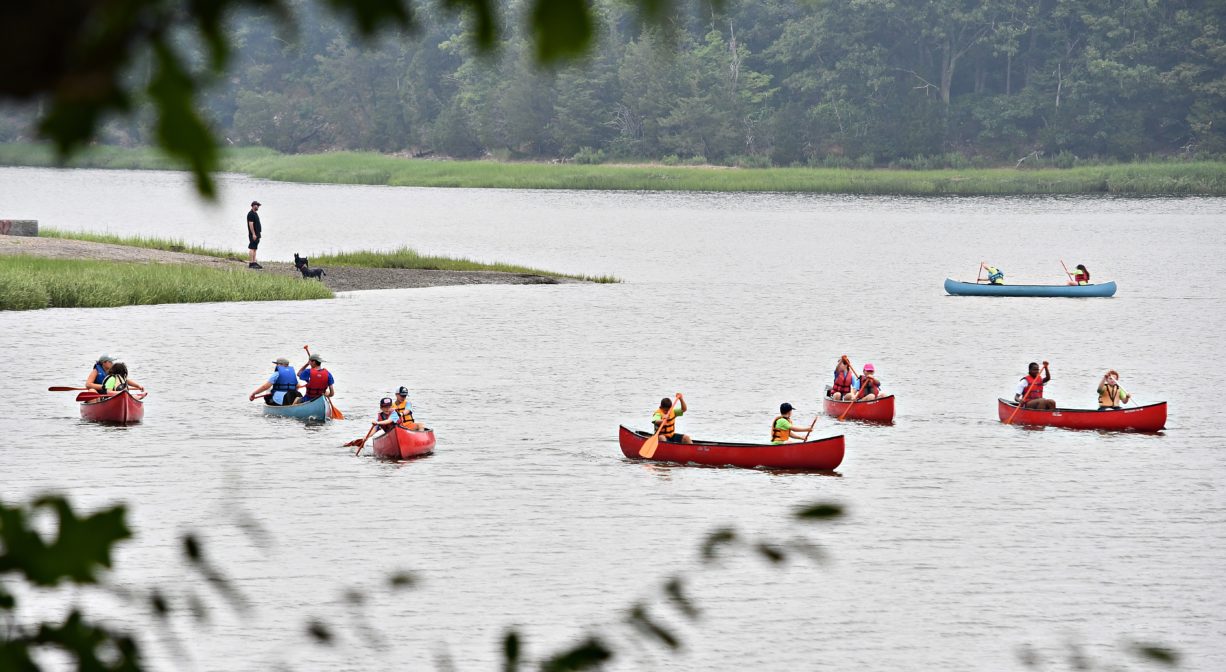 A photograph of several canoes with children in them on a river.