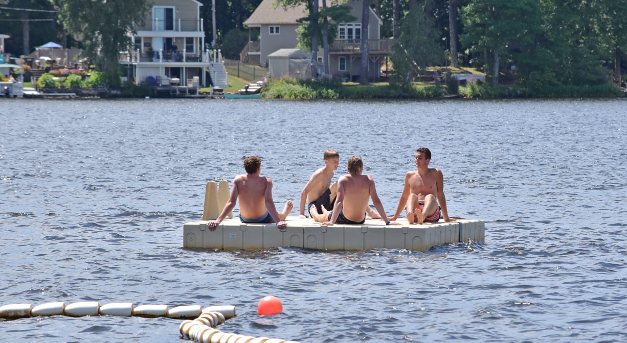 A photograph of children sitting on a float in a pond.