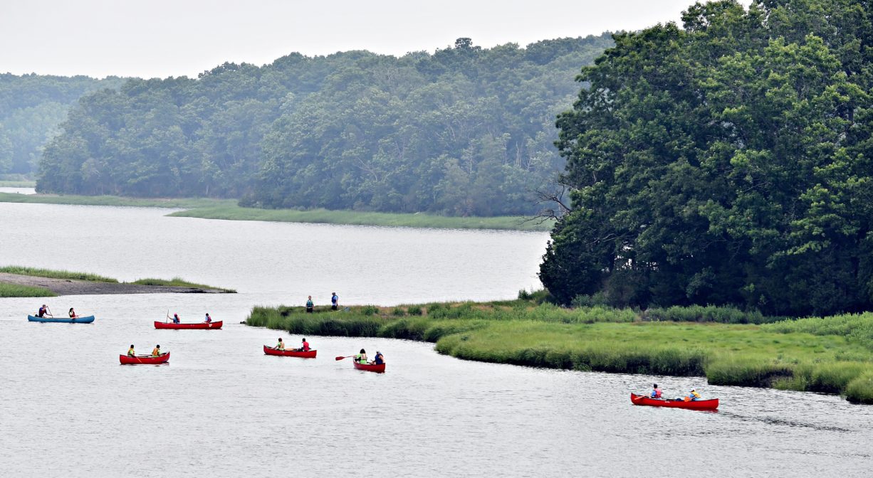 A photograph of a river with several canoes on it.
