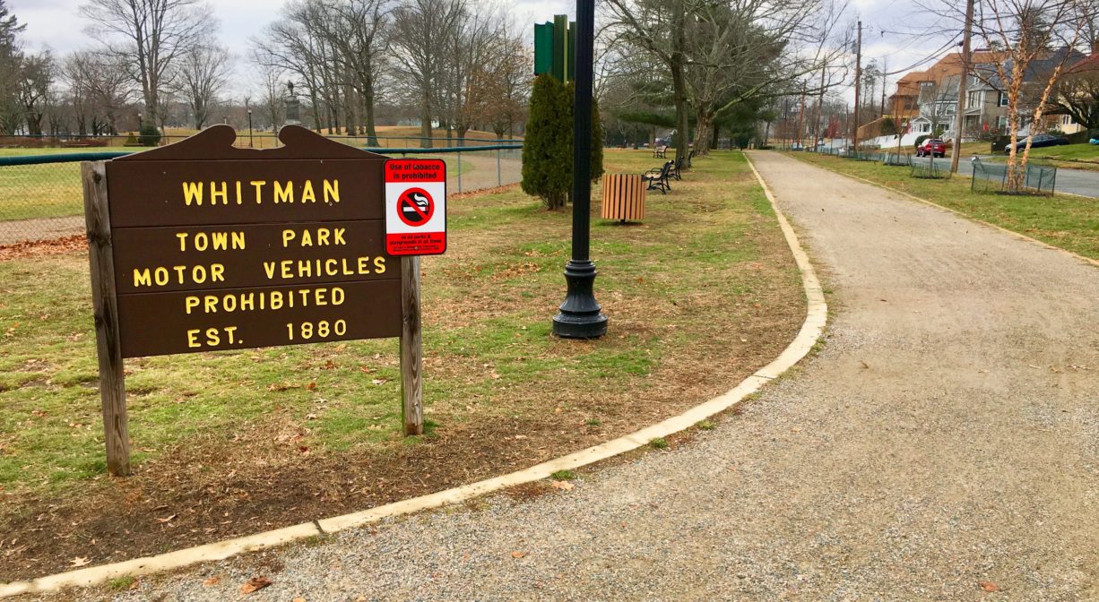 A photograph of a property sign beside a gravel path in a park.