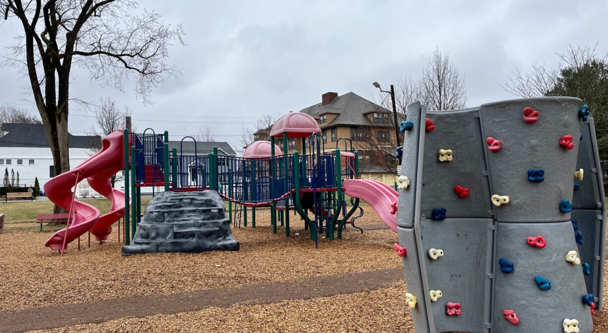 A photograph of a playground with a climbing wall and play equipment.