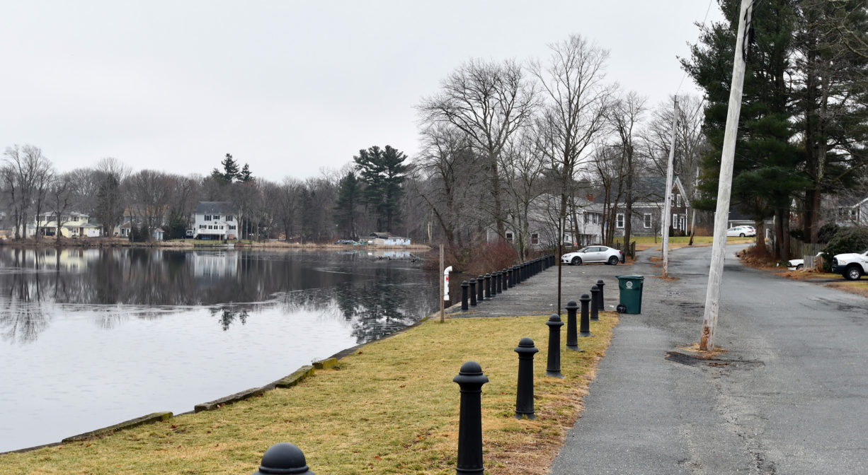 A photograph of a parking area beside a pond.