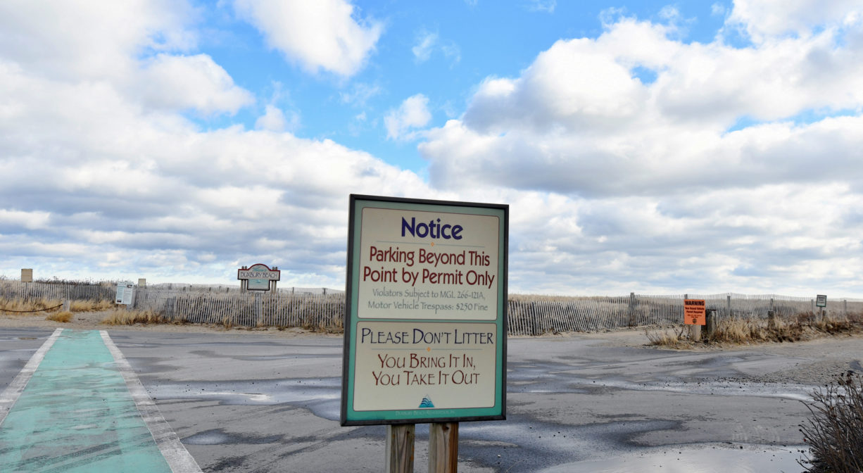 A photograph of a property sign and a parking lot, with a crosswalk.