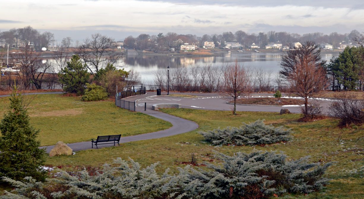 A photograph of a park, viewed from above, with a river in the background.