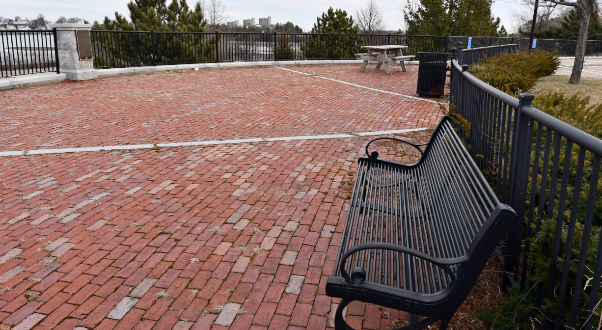 A photograph of a bench on a brick piazza.
