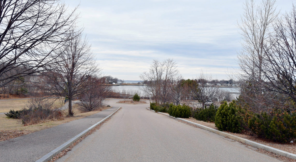 An entrance road with a river in the background.