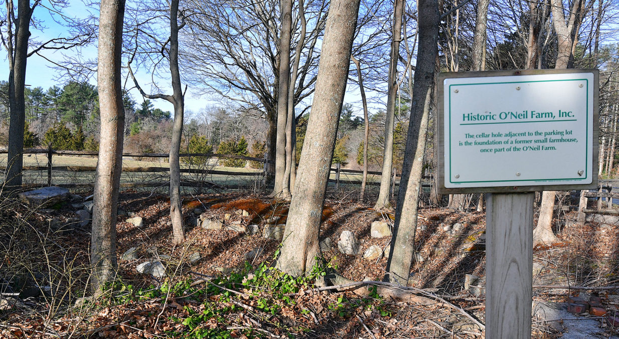 A photograph of a property sign with agricultural lands in the background.