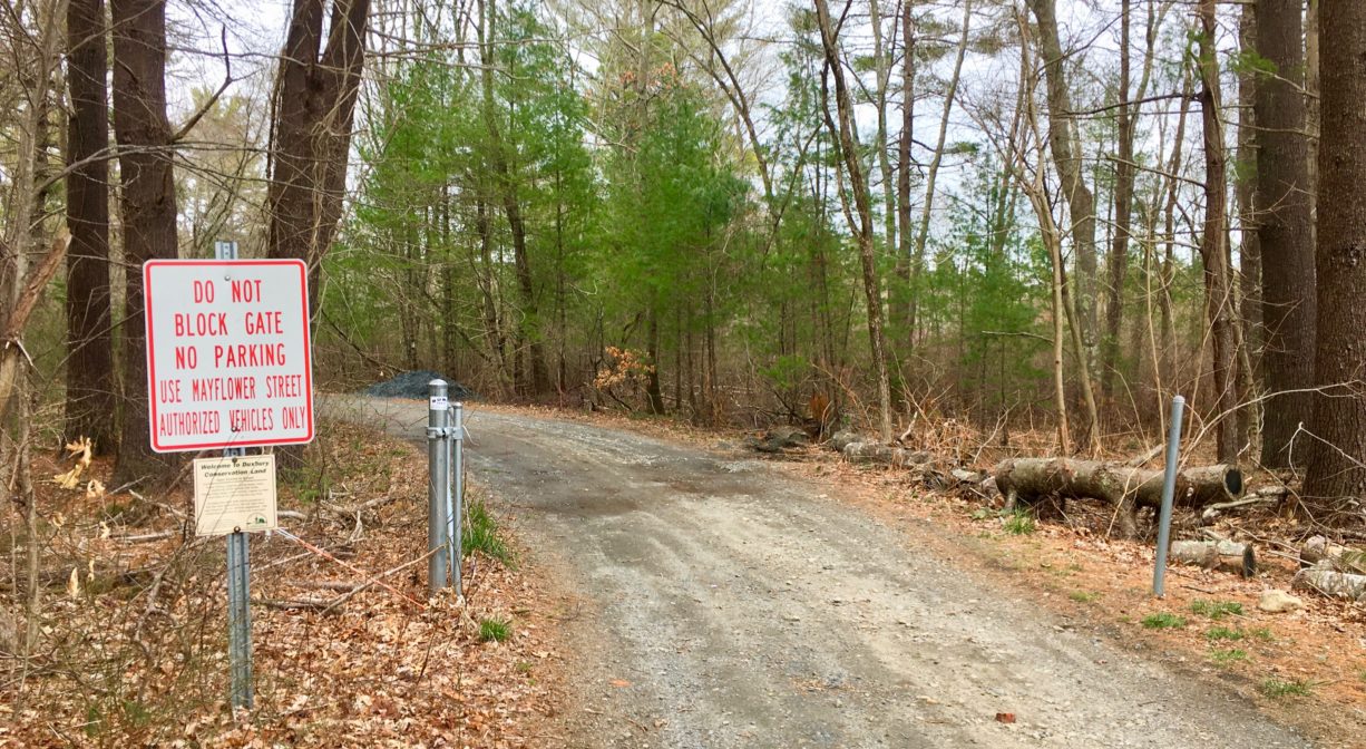 A photograph of a trail in a forest with a property sign.