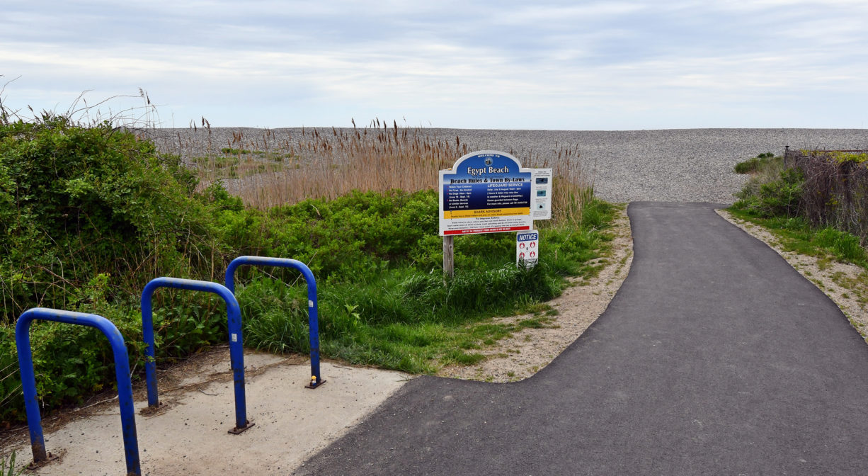 A paved entrance path and a bicycle rack, plus a property sign.