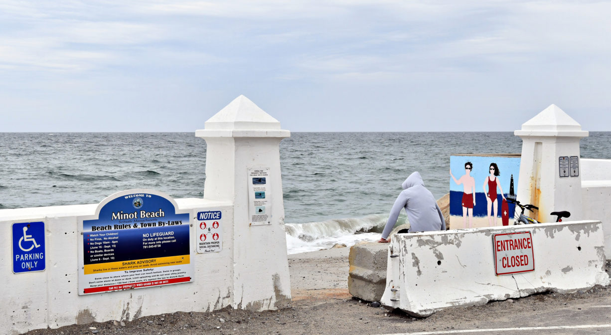 A photograph of an entrance to a beach with some property signs.