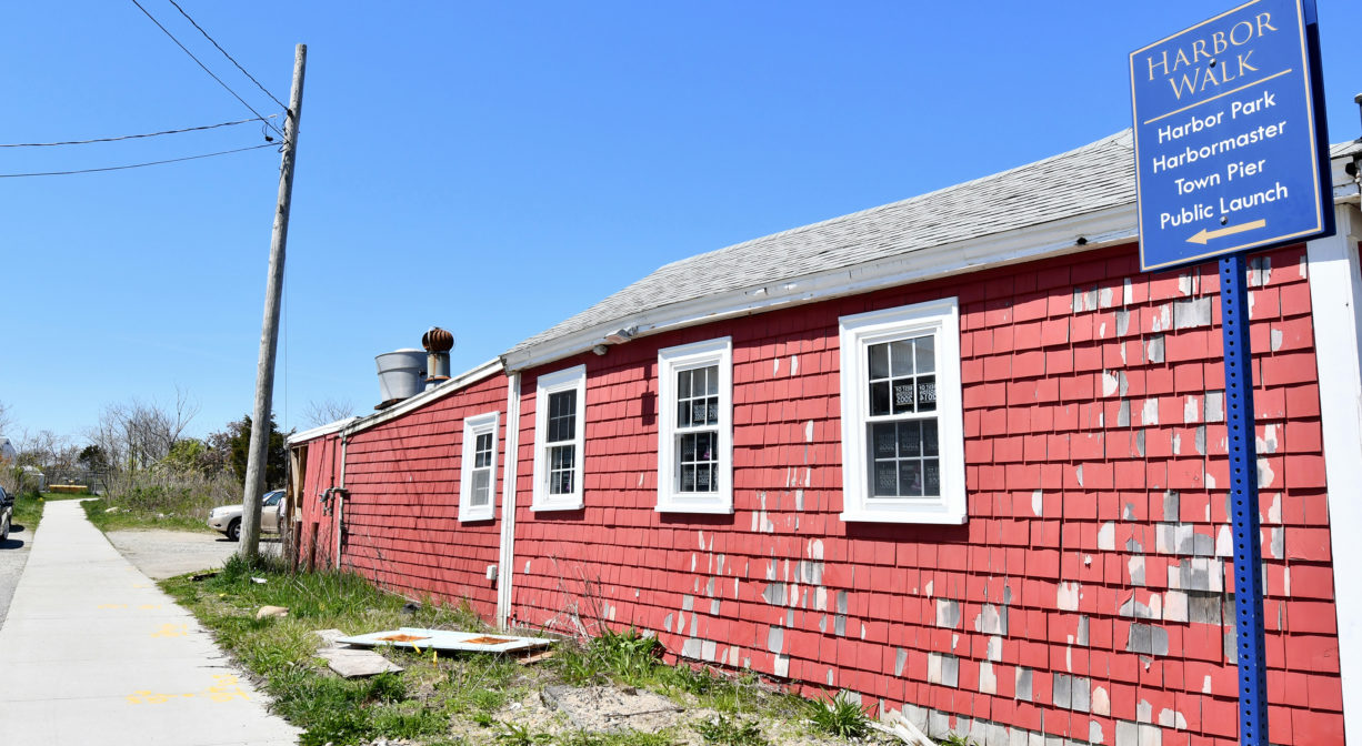 A photograph of a property sign beside a red building.