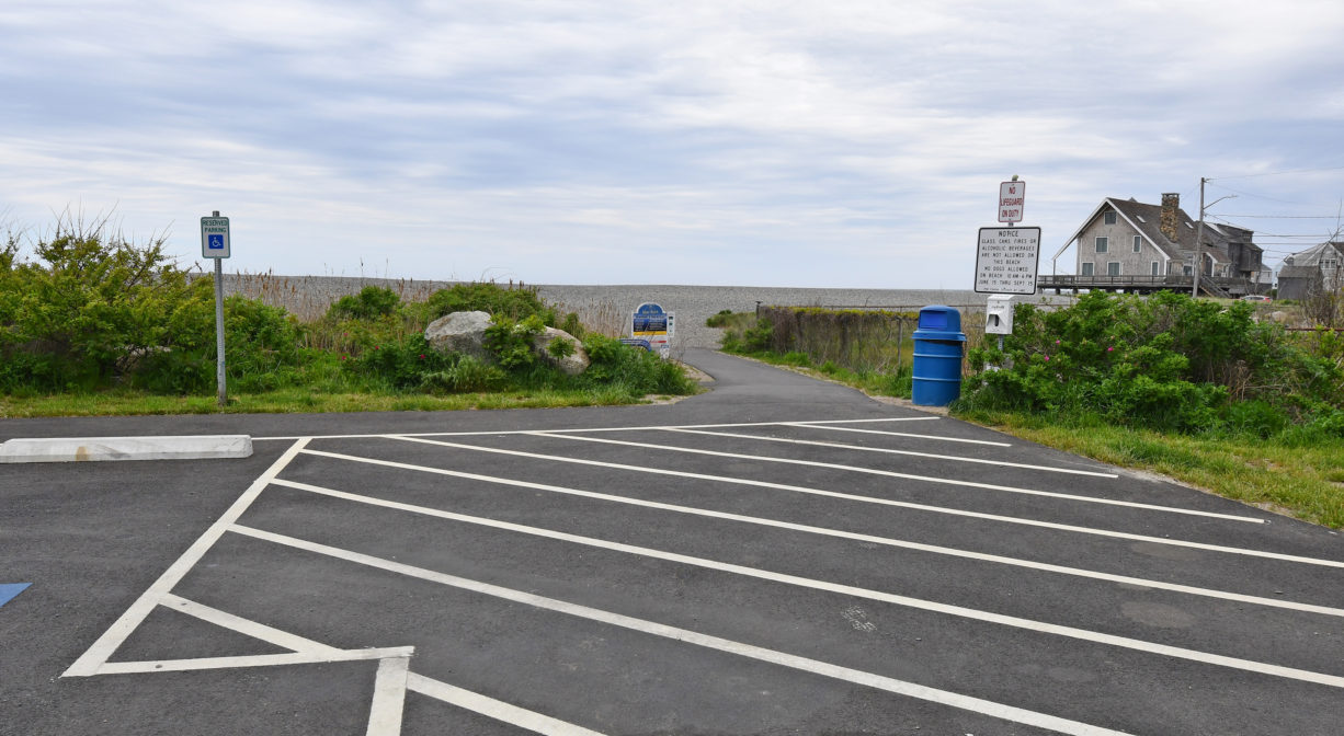 A paved pathway that heads toward a beach.