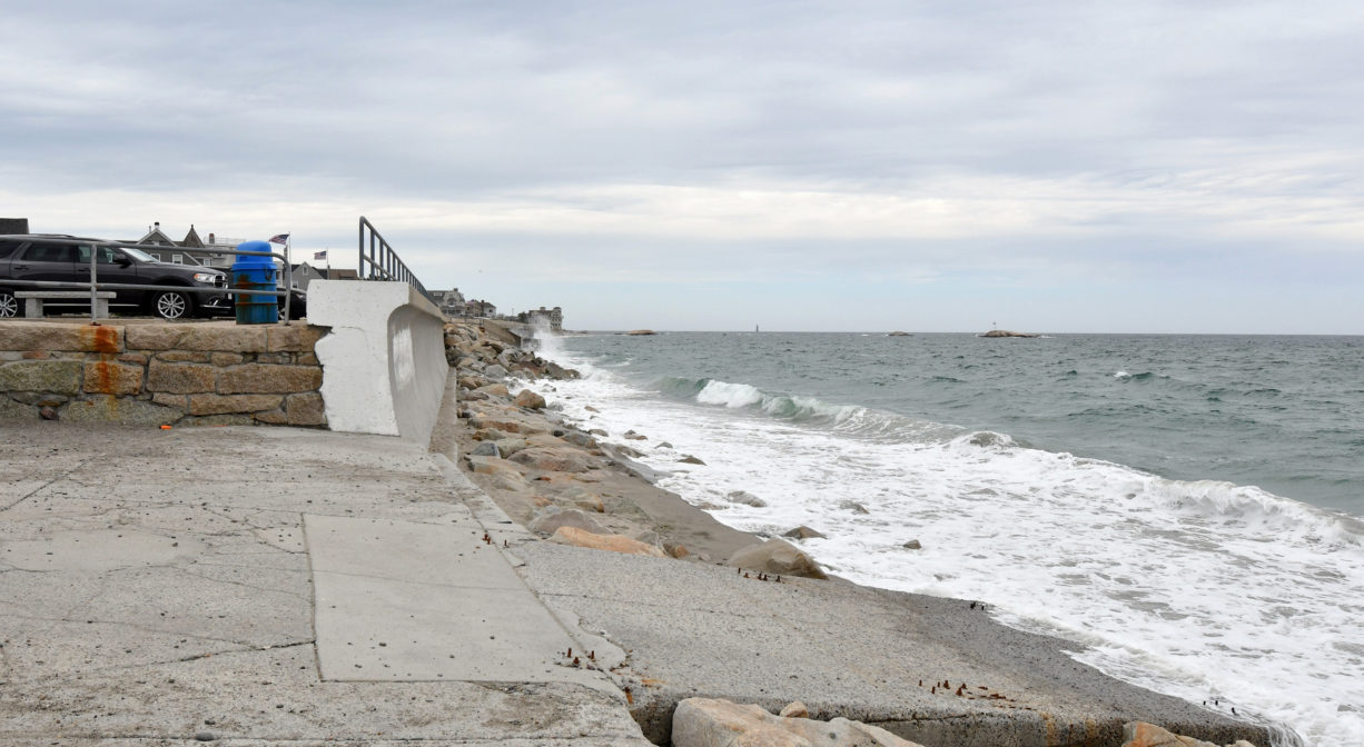 A photograph of a concrete ramp leading to a beach, with a sea wall at high tide.