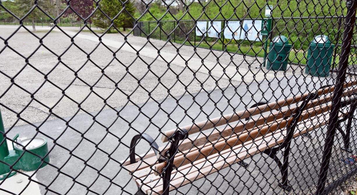 A photograph of fenced-in area with a bench.