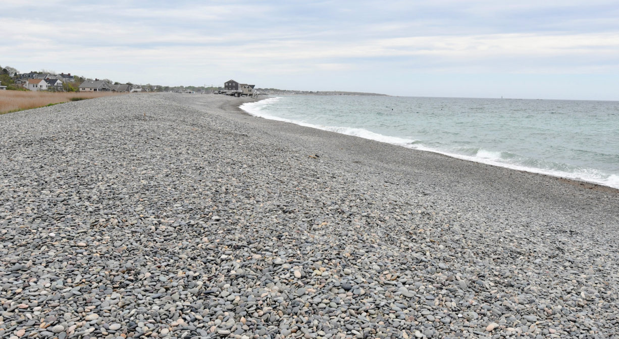 A stony beach with the ocean on one side.