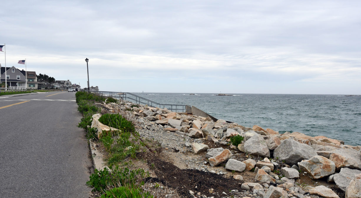 A photograph from the roadside of a rocky beach.