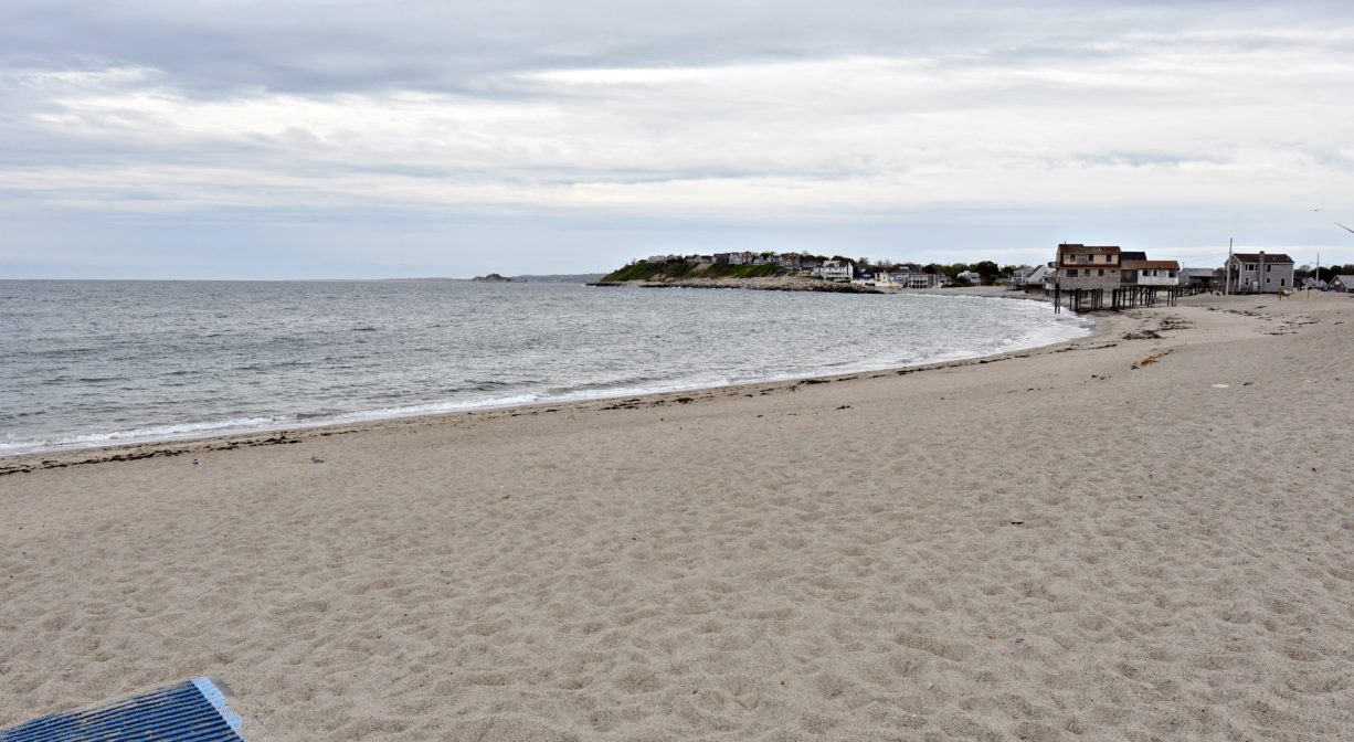 A photograph of a beach with houses in the distance.
