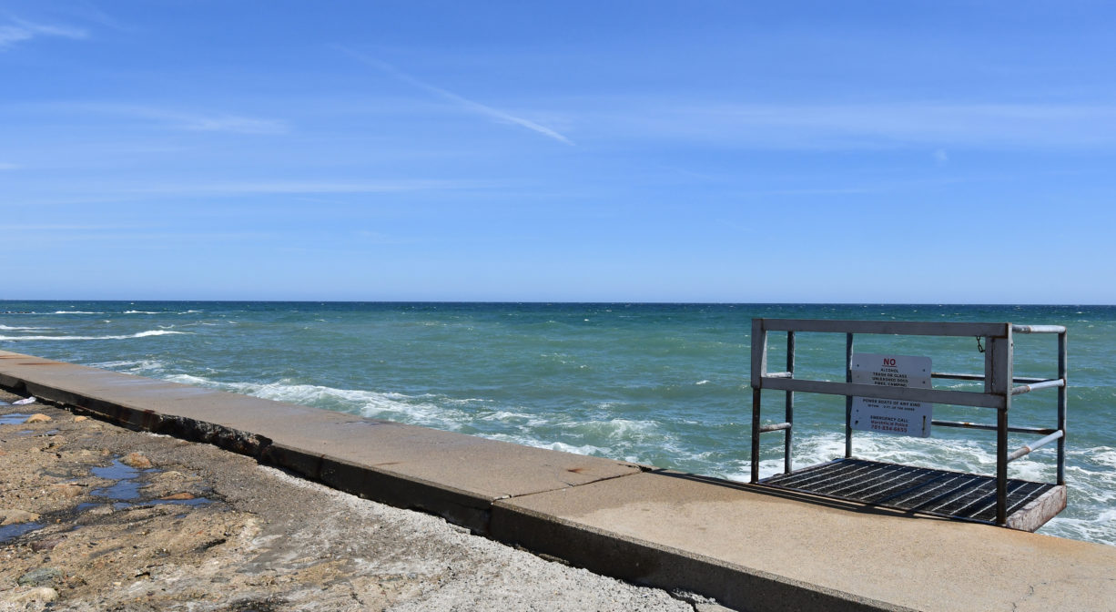 A photograph of a seawall with a staircase, with the ocean in the background.