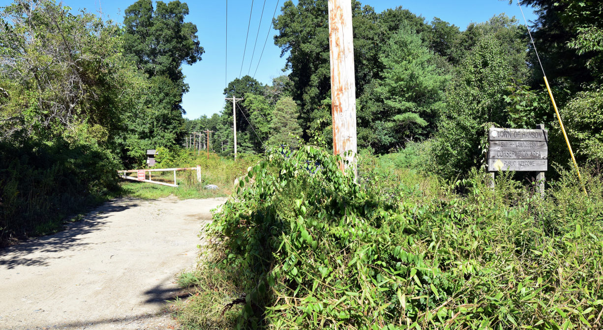 A photograph of a property sign beside an entrance road.