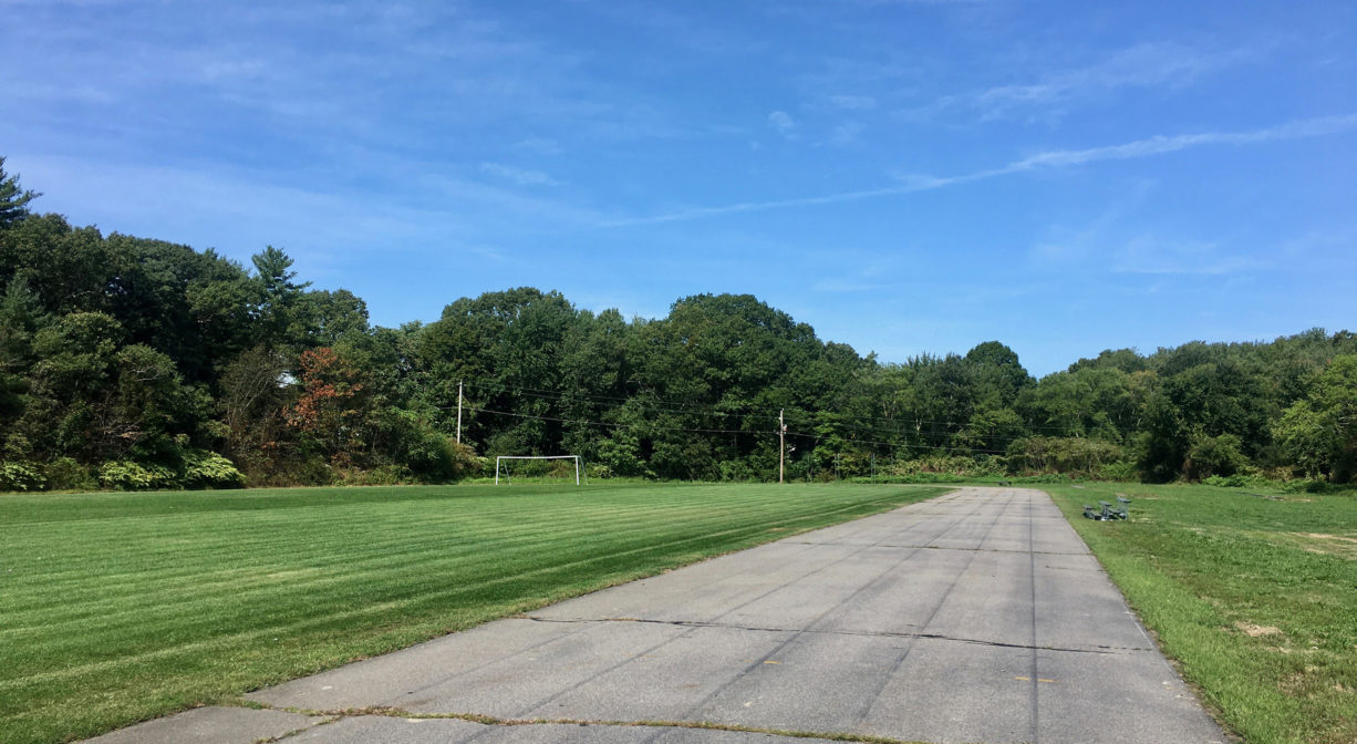 Photograph of a wide asphalt track with grass along its sides and blue skies.