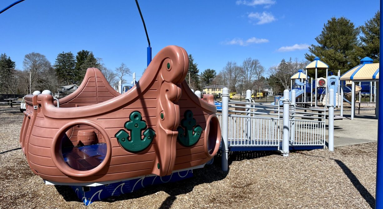 A photograph of a play structure shaped like a ship, within a playground.
