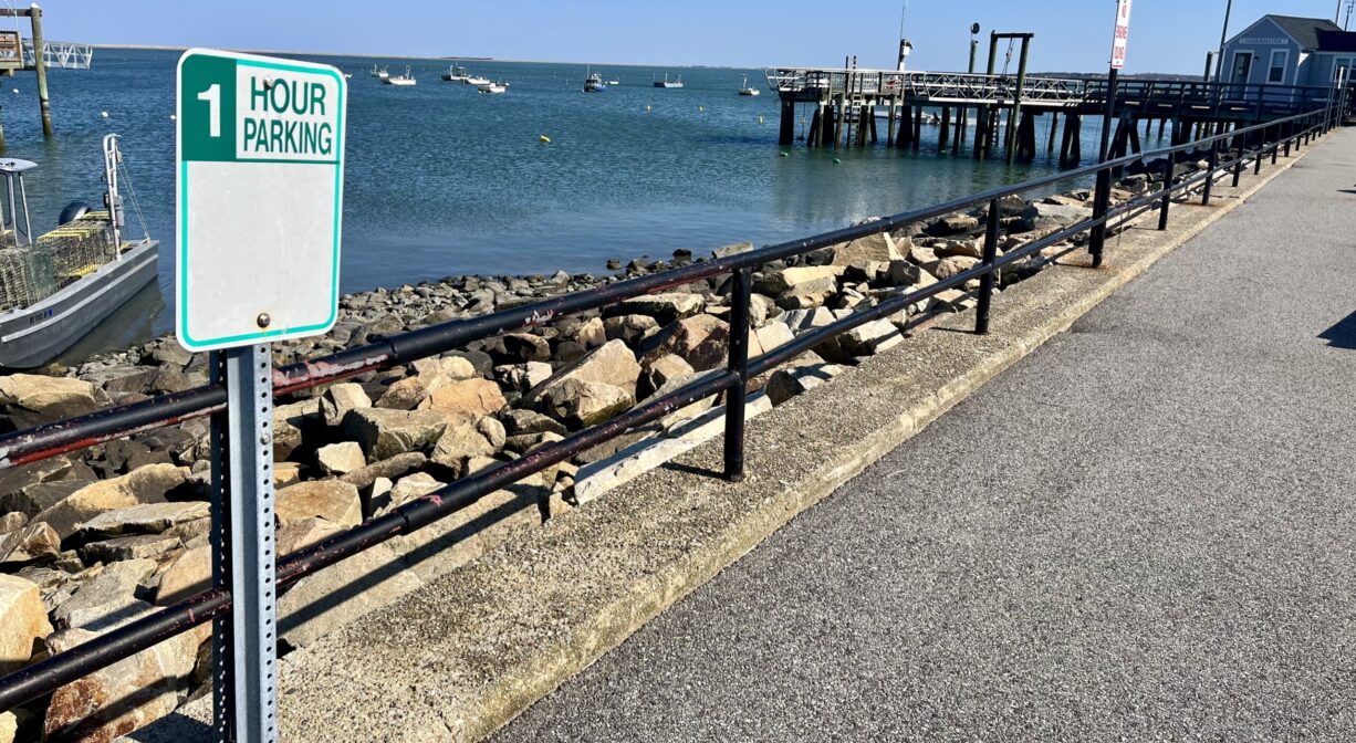 A photograph of a parking area with a pier in the background.