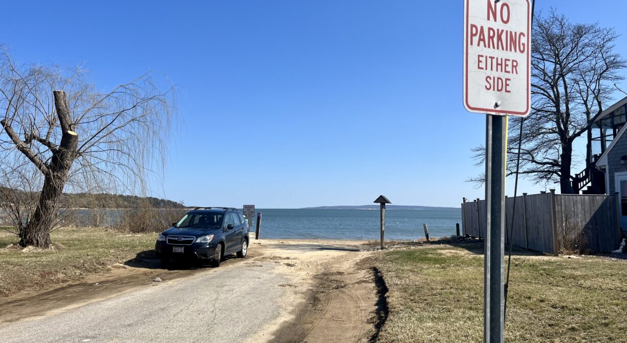 A photograph of a road approaching a beach with a 
